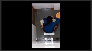 Indian girl changes pad on toilet in bathroom